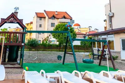 a playground with white chairs and a swing at House Apartments Black sea Hotel in Obzor