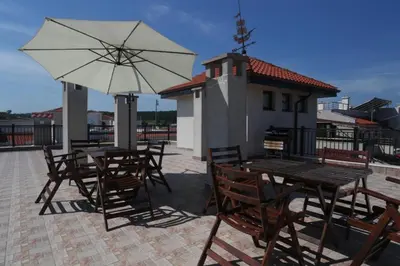 a group of tables and chairs with an umbrella at Sozopol Dreams apartman 42 in Sozopol