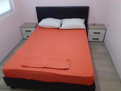 a bed with an orange blanket and two night stands at Varna beach in Varna City