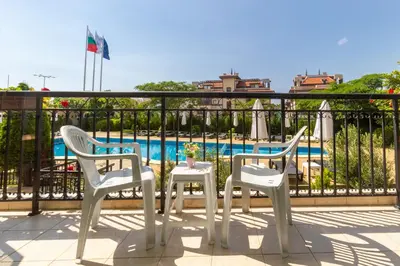 three chairs and a table on a balcony with a pool at Hotel Julia in Sveti Vlas