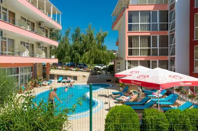 a swimming pool with an umbrella and people sitting in chairs at Iris Beach Hotel in Sveti Vlas