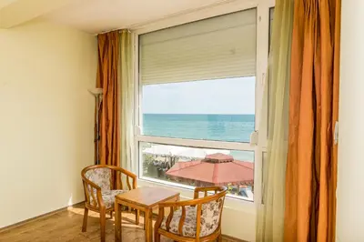 a window with a table and chairs looking out at the ocean at Iris Beach Hotel in Sveti Vlas