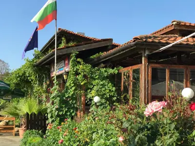 a flag flying in front of a building with flowers at Bisser Obzor in Obzor