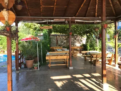 a wooden pavilion with tables and benches in a yard at Bisser Obzor in Obzor
