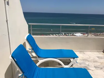 a pair of blue chairs on a balcony with the beach at Bisser Obzor in Obzor