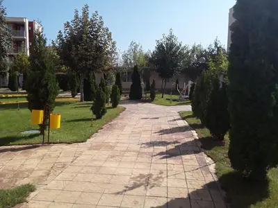 a walkway in a park with trees and a building at FORT NOKS NESSEBAR B2-203 Private Studio Sunny Beach in Sunny Beach