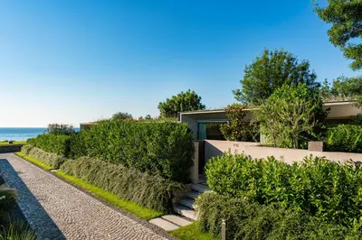 a house with a walkway and bushes next to the ocean at Vaya Beach Resort in Emona