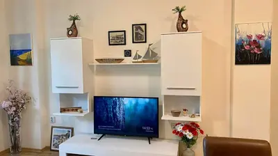 a living room with a tv and white shelves at Sozopol Dreams apartman 35 in Sozopol