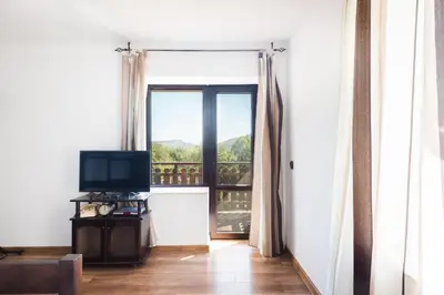 a room with a door open to a balcony with a television at Guest House Hristova Kashta - Христова Къща in Cherni Vrŭkh