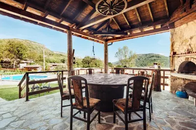 an outdoor patio with a table and chairs and a fireplace at Guest House Hristova Kashta - Христова Къща in Cherni Vrŭkh