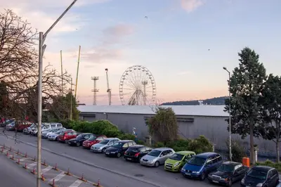 a row of cars parked in a parking lot with a ferris wheel at LunApart in Varna City