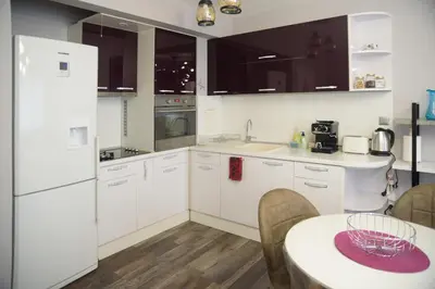 a kitchen with white appliances and a table and a table and chairs at Apartment MARTINI in Burgas City
