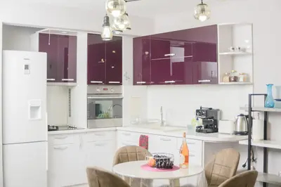 a kitchen with white cabinets and a table with chairs at Apartment MARTINI in Burgas City