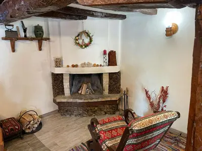 a living room with a fireplace and two chairs at СЪНТОВЕЦ - на брега на язовир Цонево in Tschenge