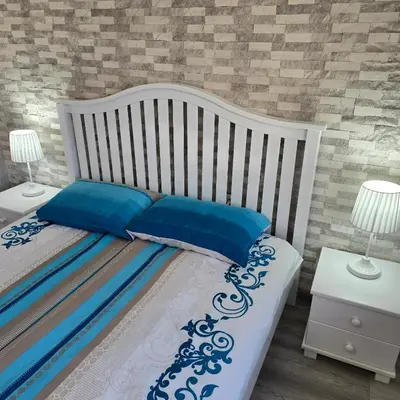 a white bed with blue pillows and two night stands at Aпартамент 5 in Varna City