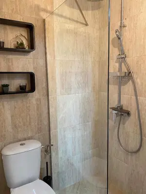 a bathroom with a shower with a toilet and a glass door at Stylish URBAN Apart New 2021 Close to the Beach in Varna City