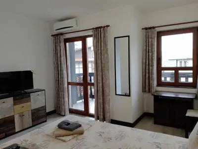 a bedroom with a bed and a television and windows at Pearl Apartments Sozopol in Sozopol