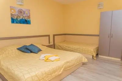 two beds in a room with yellow walls at Къща за гости КАТИ in Kiten