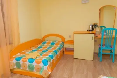 a small bedroom with a bed and a kitchen at Къща за гости КАТИ in Kiten
