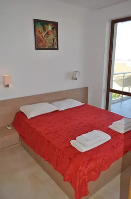a bedroom with a bed with red sheets and a window at Beautiful family villa with sea view in Byala