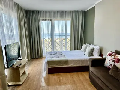 a bedroom with a bed and a couch and a television at Teos Apartments Primorsko in Primorsko