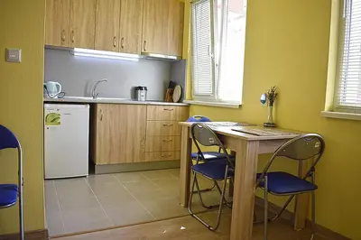 a kitchen with a table and chairs and a refrigerator at Starlight Studios in Burgas City