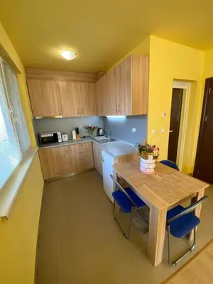 a small kitchen with a wooden table and blue chairs at Starlight Studios in Burgas City