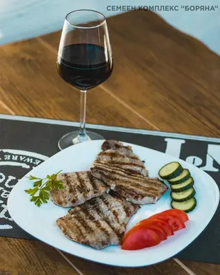a plate of meat and vegetables with a glass of wine at Boryana Hotel in Burgas City