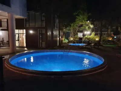 a large blue pool in a courtyard at night at Апартамент За Гости ,,ХРИСТИНА