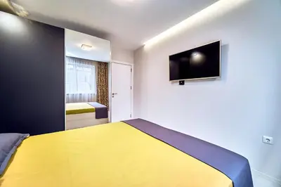 a bedroom with a yellow bed and a flat screen tv at Апартамент S Apart in Varna City