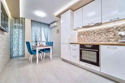 a kitchen with white cabinets and a table and chairs at Апартамент S Apart in Varna City