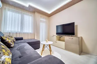 a living room with a blue couch and a tv at Апартамент S Apart in Varna City