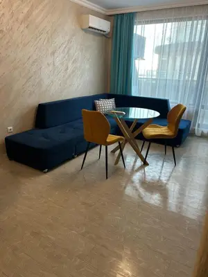 a living room with a blue couch and a glass table at Апартамент Анели in Pomorie