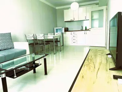 a living room and kitchen with a couch and a table at Apartments Stamopolu Lux with pool view in Primorsko