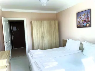 a bedroom with a large bed with white sheets at Apartments Stamopolu Lux with pool view in Primorsko