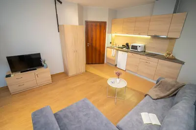 a living room with a blue couch and a kitchen at Via Pontica 123 Guest Apartments in Sozopol