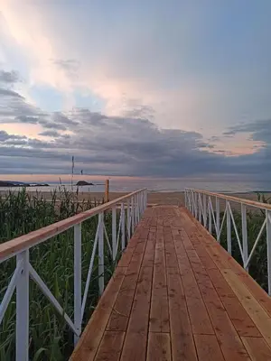 a wooden boardwalk leading to the beach at sunset at Apartment Relax Lozenets in Lozenets