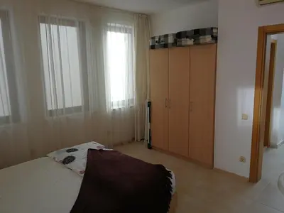 a bedroom with a bed and a cabinet and windows at Cozy family villa 500m. from the beach in Byala