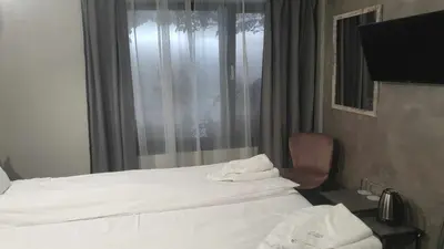 a hotel room with a bed and a chair and a window at Boutique Guest House