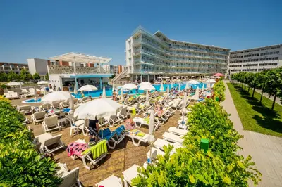 a beach with chairs and umbrellas and a pool at Aqua Nevis Hotel & Aqua Park - All Inclusive in Sunny Beach