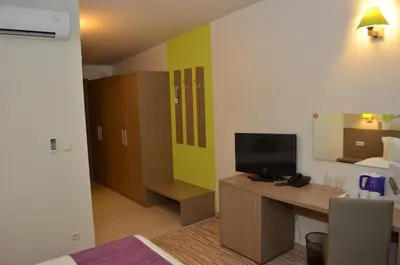 a room with a desk with a television and a bed at Aqua Nevis Hotel & Aqua Park - All Inclusive in Sunny Beach
