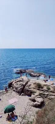 a group of people on a beach with an umbrella at ЛЕСО-Зара студио in Ravda