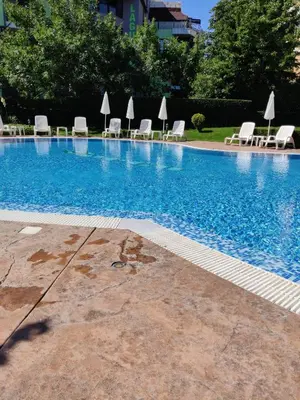 a large swimming pool with white chairs and umbrellas at ЛЕСО-Зара студио in Ravda