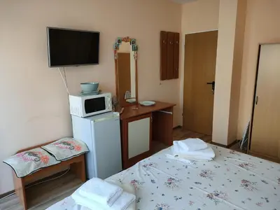 a room with two beds and a microwave on top of a refrigerator at Самостоятелни стаи Виктория in Pomorie