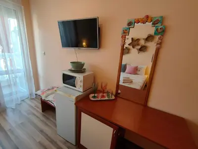 a small room with a television on top of a refrigerator at Самостоятелни стаи Виктория in Pomorie