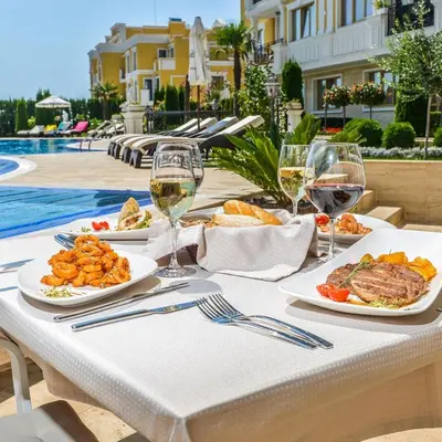 a table with plates of food and glasses of wine at FLORENCE SUITES APART HOTEL in Sveti Vlas