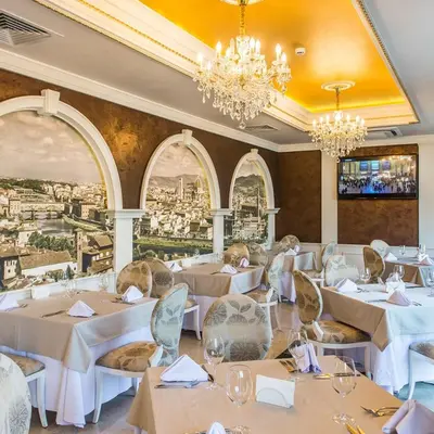 a restaurant with white tables and chairs and chandeliers at FLORENCE SUITES APART HOTEL in Sveti Vlas
