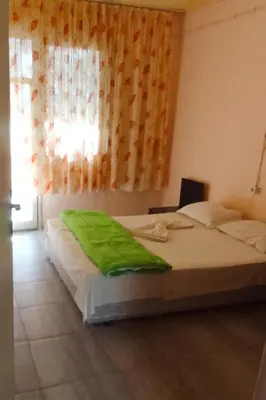 a bedroom with a bed with a green blanket on it at Бунгала Дъбрава in Shkorpilovtsi