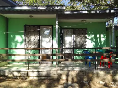 a green house with a table and chairs on a porch at Бунгала Дъбрава in Shkorpilovtsi