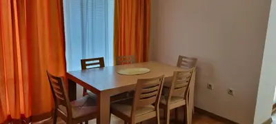 a dining room table and chairs with an orange curtain at Dani beach Sozopol in Sozopol